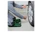 Personne agenouillée sur un tapis de travail, utilisant une clé en croix pour changer un pneu de voiture.