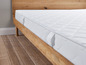 Un matelas blanc sur un cadre de lit en bois.