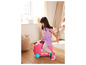 Une enfant est assise sur une valise rose avec Peppa Pig.