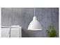 Un luminaire suspendu blanc au-dessus d'une commode blanche avec une plante verte.