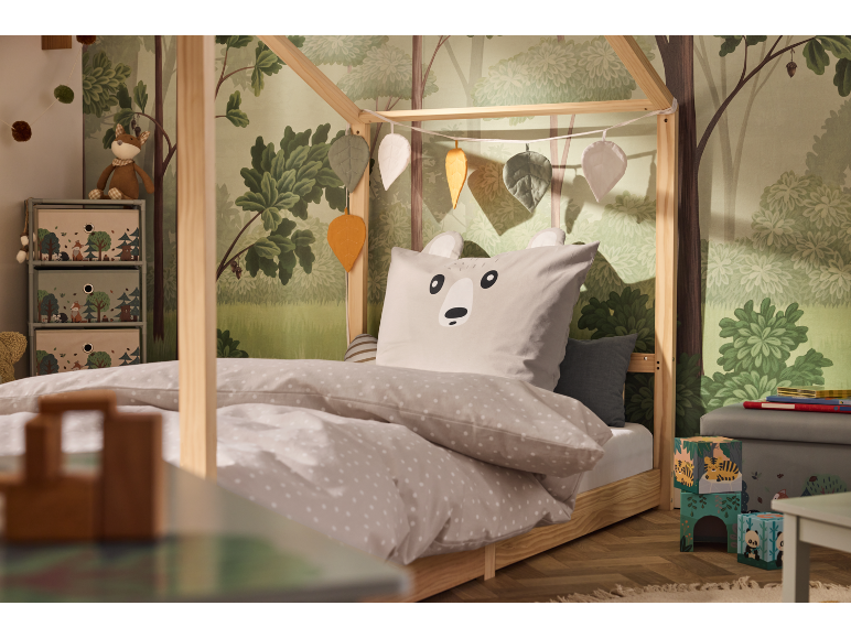 Lit d'enfant avec papier peint sur le thème de la forêt et literie sur le thème des animaux.