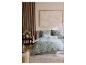 Chambre avec parure de lit florale vert menthe, lambris en bois et tableau.