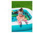 Une fille dans une piscine gonflable à thème tropical avec des jouets de piscine roses.