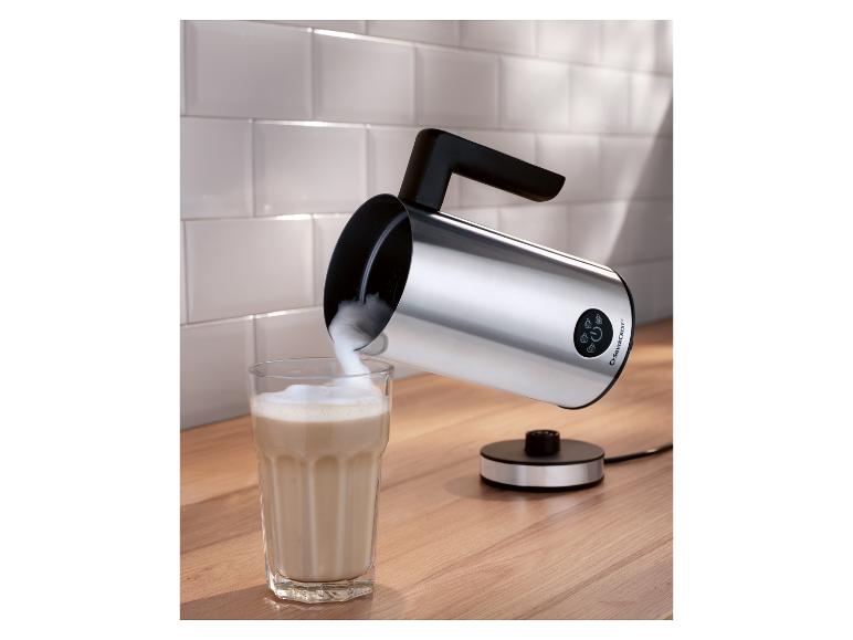 Mousseur à lait Silvercrest argenté sur un comptoir en bois, versant de la mousse dans un verre.