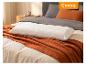 Oreiller blanc texturé sur une couverture orange et une literie grise dans une chambre