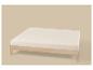 Lit double en bois clair avec matelas blanc sur fond beige.