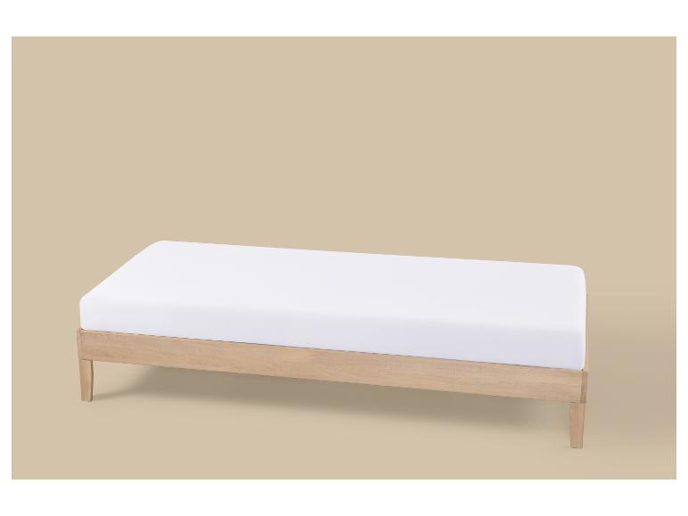Lit de jour en bois clair avec matelas blanc sur fond beige