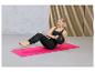 Une femme fait de l'exercice sur un tapis rose avec un ballon d'exercice.