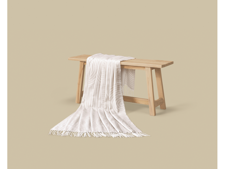 Plaid crème à motifs de rayures et de cercles sur un banc en bois.