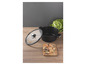 Une casserole noire avec un couvercle en verre et des pâtes sur une planche à découper en bois.