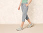 Une femme porte un pantalon capri gris et des baskets vertes.