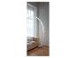 Un lampadaire en arc argenté dans un salon moderne avec un canapé beige.