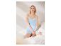 Femme en pyjama bleu clair avec de la dentelle blanche, assise sur un lit blanc.