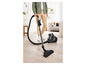 Une personne utilisant un aspirateur noir sur un sol en bois.