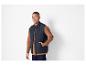 Un homme porte un gilet bleu marine sur une chemise marron.