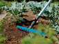 Un râteau Gardena bleu dans un jardin avec du brocoli.