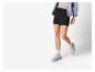 Femme portant un short noir et des baskets grises.