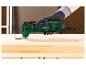 Un outil multifonction Parkside PMFW 310 H5 vert dans une main sur un fond en bois.