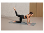 Une femme en leggings noirs et soutien-gorge de sport fait du yoga sur un tapis gris.