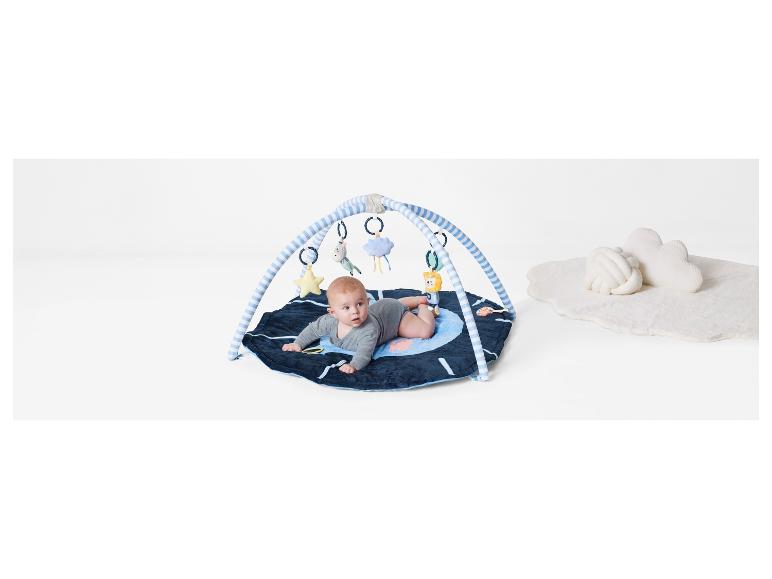 Un bébé allongé sur un tapis de jeu avec un arc et des jouets