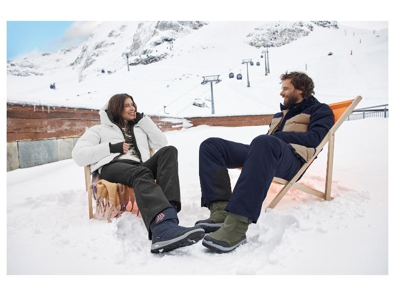 Deux personnes se détendent dans des chaises longues sur la neige, portant des vestes et pantalons de ski.