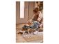 Femme caressant un chien avec harnais et laisse dans l'entrée sur un tapis.