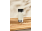 Bouteille isotherme crème avec couvercle noir et grains de café sur une surface en bois.