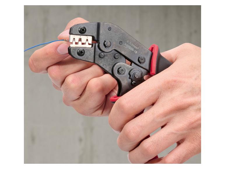 Une personne utilise une pince à sertir pour connecter un fil bleu.