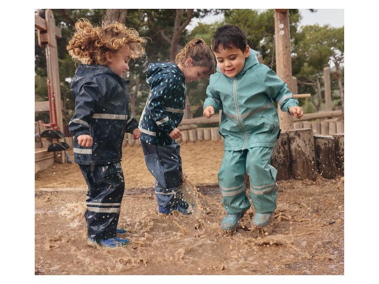 Des enfants s'amusent dans les flaques de boue avec des imperméables colorés.