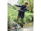 Un homme en veste bleue et pantalon vert se tient dans un ruisseau.