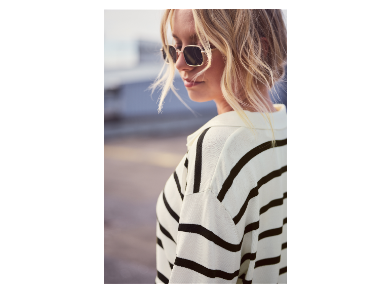 Une femme dans un pull rayé portant des lunettes de soleil.