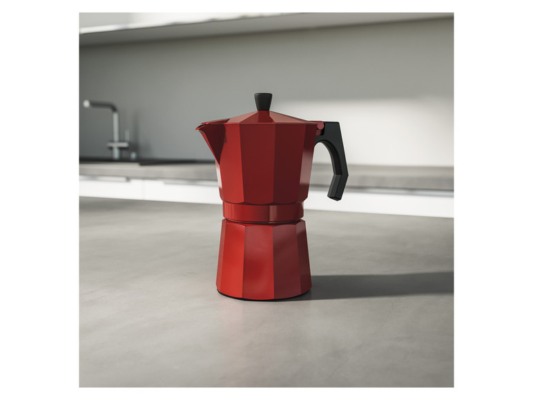 Une cafetière rouge sur un comptoir.