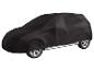 Voiture recouverte d'une bâche de protection noire, avec roues et bas de caisse visibles.