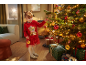 Une jeune fille en pull de Noël rouge décorant un sapin de Noël avec des boules.