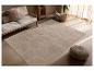 Tapis beige à motifs géométriques dans un salon moderne avec canapé et pouf.