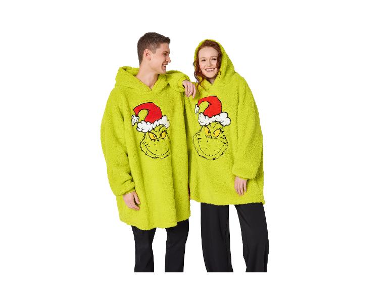 Deux jeunes souriants portent des sweats à capuche Grinch surdimensionnés