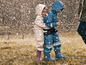 Deux enfants en vêtements de pluie et en bottes jouent sous la pluie.