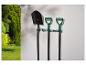 Outils de jardin Parkside: pelle et bêches accrochées à un mur dans un jardin.