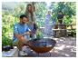 Famille cuisinant en extérieur avec une cocotte en fonte dans un brasero et une caisse en bois.