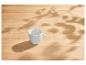 Tasse blanche sur une table en bois clair avec des ombres de feuilles