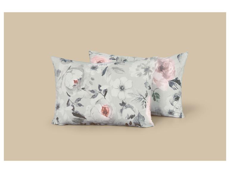 Deux oreillers à motif floral de roses grises et roses sur fond beige.