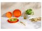 Soupe verte dans des bols orange, huile d'olive, plante de basilic et planche en bois avec herbes.
