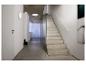 Couloir minimaliste avec escalier en béton, mur en verre et luminaires muraux et de plafond blancs.