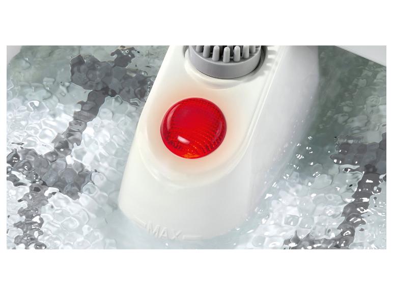 Une lumière rouge éclaire le panneau de contrôle d'un spa pour les pieds, partiellement immergé dans l'eau.