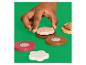 Main d'enfant plaçant un biscuit en bois rose avec des vermicelles sur une base marron.