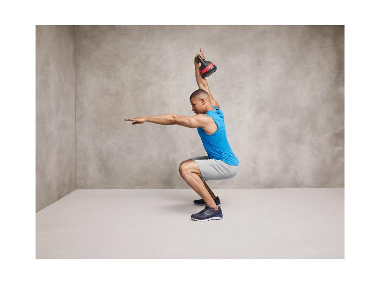 Homme en débardeur bleu avec des baskets noires et une kettlebell.
