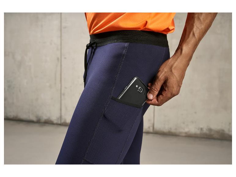 Un homme portant un pantalon de survêtement noir avec un téléphone dans la poche.