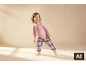 Fille souriante en pyjama rose avec imprimé croissant et pantalon à carreaux.