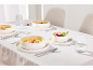 Table élégamment dressée avec des bols en céramique blanche contenant de la soupe et un dessert, des verres et des couverts