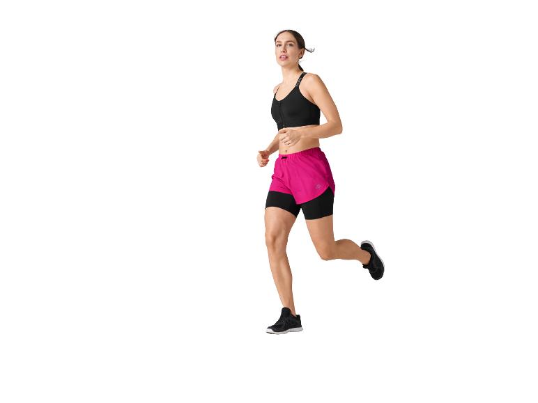 Une femme court, vêtue d'un soutien-gorge de sport noir et de shorts roses.